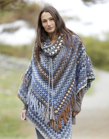 A woman wearing a blue and brown crocheted poncho.