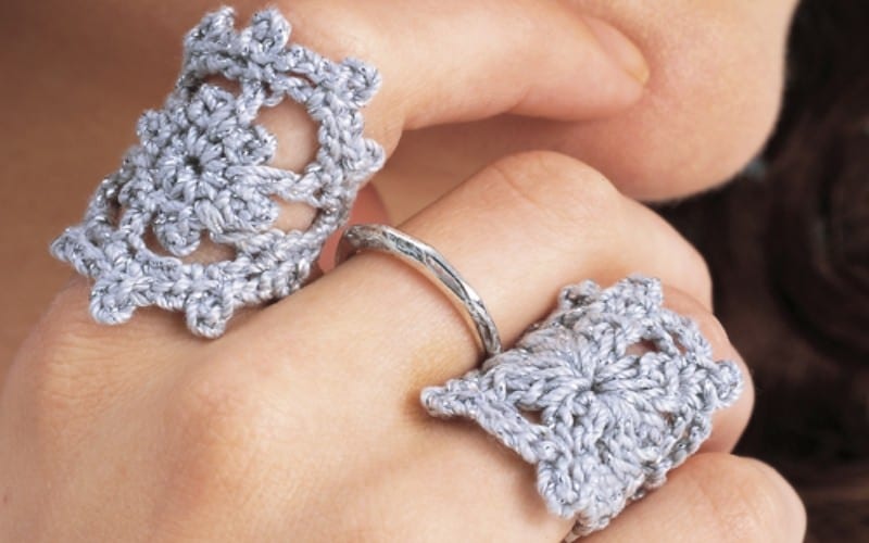 Close-up of hands adorned with girly crochet rings, featuring two delicate designs and a sleek silver band ring.