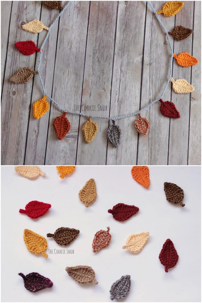 Crocheted autumn leaves in various colors are arranged on a wooden surface and displayed as a garland, making beautiful crochet decorations for fall.