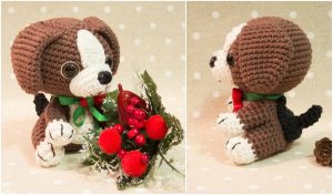 This adorable amigurumi dog, resembling a beagle puppy, features crocheted brown and white details with a green ribbon. It sits charmingly next to a sprig of red berries and leaves, adding a delightful touch to any space.