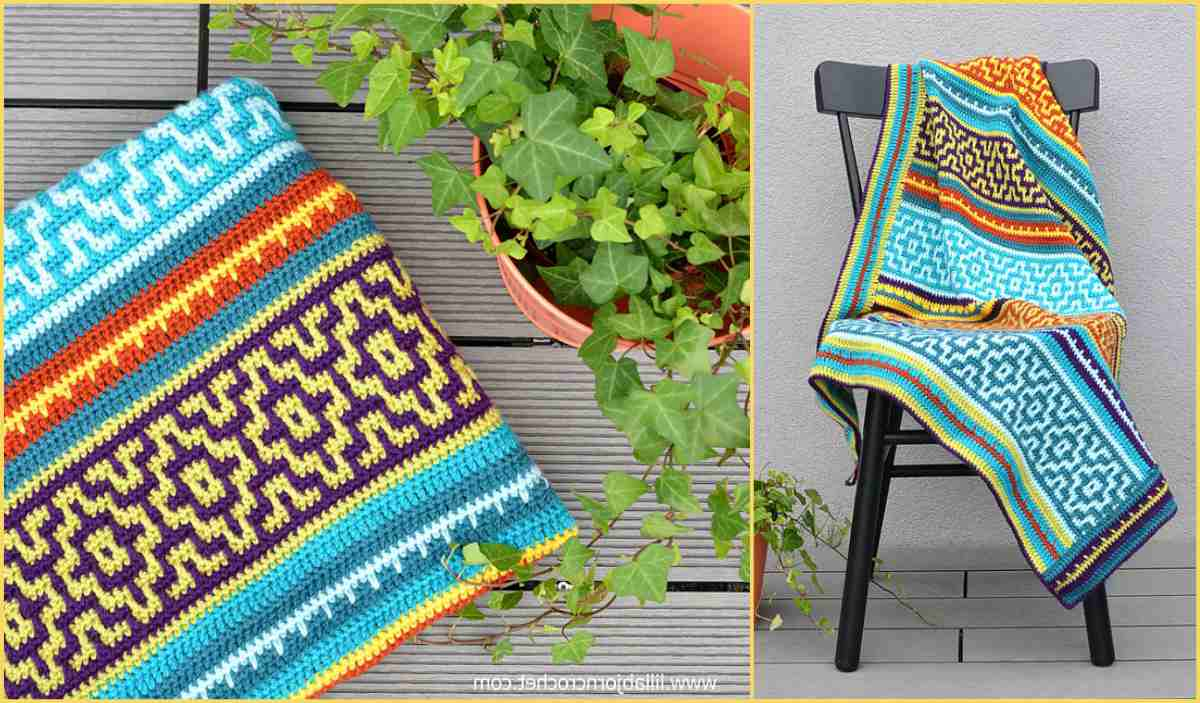 A vibrant mosaic blanket with intricate geometric patterns is draped over a black chair on a gray deck. Nearby, a potted ivy plant adds a touch of greenery.