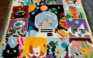 A vibrant crocheted afghan showcases pixel art designs of cute cats and a dog in a spacesuit, all arranged in a charming grid pattern. Perfect for enthusiasts seeking lively free crochet patterns.