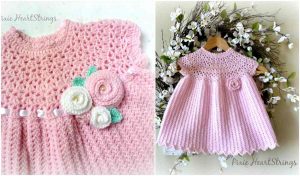 Pixie's Pretty Pink crocheted baby dress, adorned with delightful floral embellishments, gracefully hangs on a wooden hanger against a backdrop of white flowers.