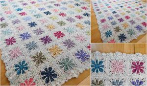 A vibrant Crochet Blanket featuring floral square patterns rests on a wooden floor. The close-up reveals intricate stitching and scalloped edges, perfect for those seeking a Free Crochet Pattern to recreate this masterpiece at home.