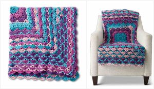 The crocheted blanket, crafted with a mesmerizing middle shell stitch in hues of purple, teal, pink, and blue, is elegantly displayed folded over a white armchair.