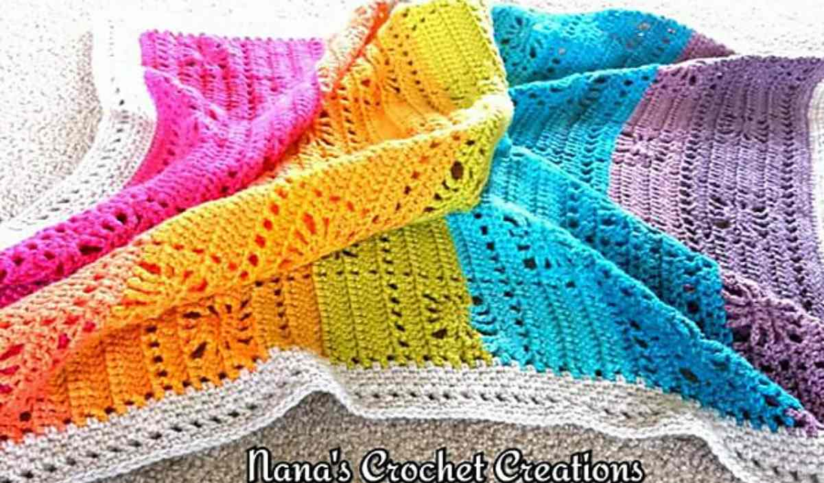 A vibrant crochet blanket featuring sections in pink, orange, yellow, green, blue, and purple on a white background. Text reads "Nana's Crochet Creations." Discover the Spiders Squared Blanket with a free crochet pattern inspired by Nana's intricate designs.