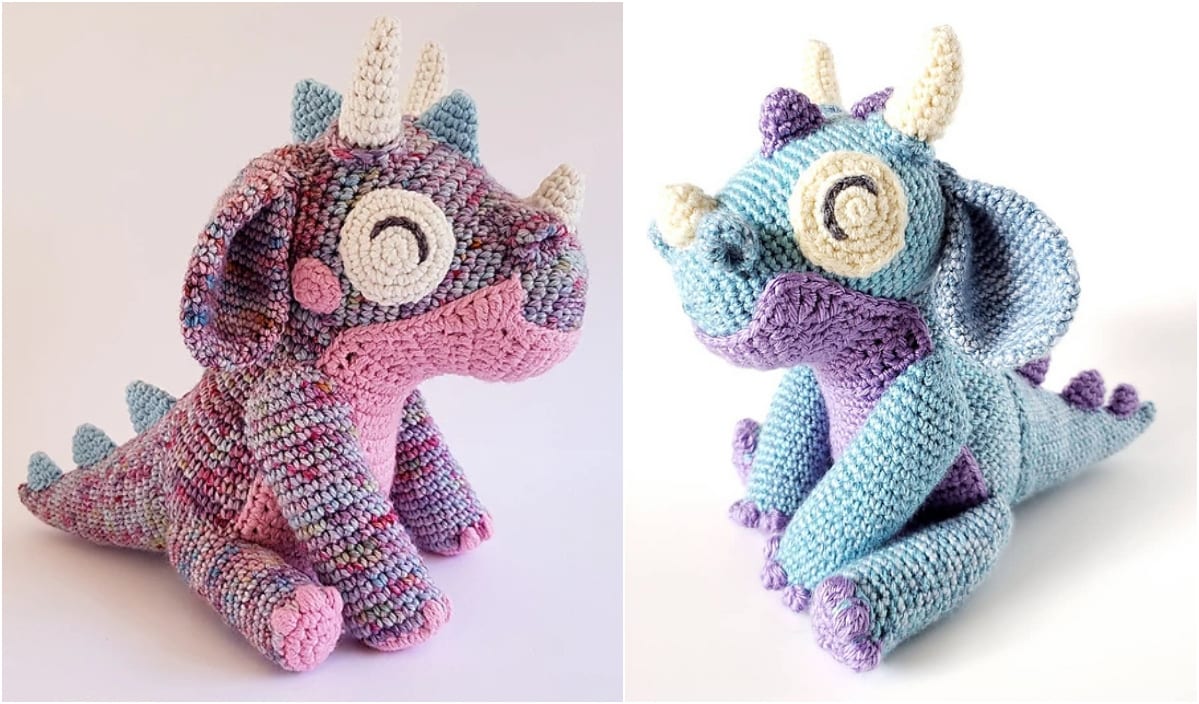 Two crocheted dragon toys crafted from a charming crochet pattern, one in pink and multicolored yarn, and the other in blue and purple. Both feature cream-colored horns and large eyes, sitting side by side.