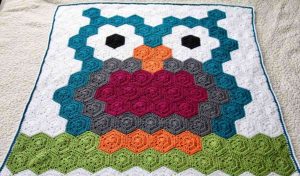 Discover our Hexagon Blanket adorned with a vibrant owl design, showcasing shades of teal, white, black, gray, pink, orange, and green on a soothing beige background. Perfect for night owl enthusiasts looking to add a cozy touch. Explore this artful creation today!