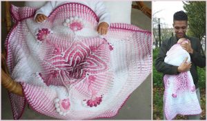 A person gently cradles a wee baby, wrapped in a pink and white crocheted blanket adorned with charming star and flower designs, reminiscent of an exquisite free crochet pattern.