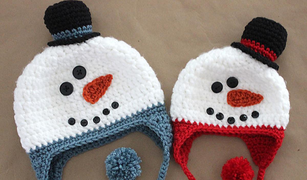 Two crocheted snowman hats feature button eyes and carrot noses. With a crochet pattern spanning newborn to adult, one hat has a blue border and pom-pom, while the other sports a red border. Both boast charming black top hats.