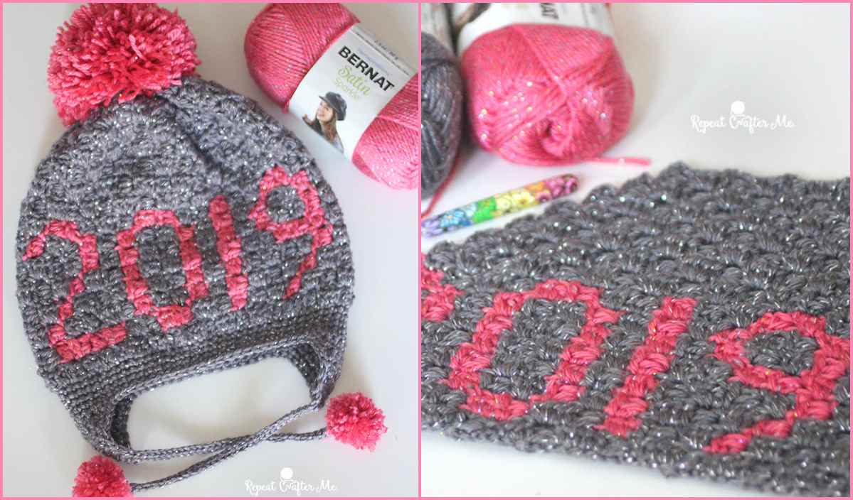 A gray knitted hat with "2019" in pink yarn and a pom-pom, displayed alongside colorful yarn balls and a crochet hook, perfect for C2C Crochet enthusiasts seeking inspiration from a free pattern.