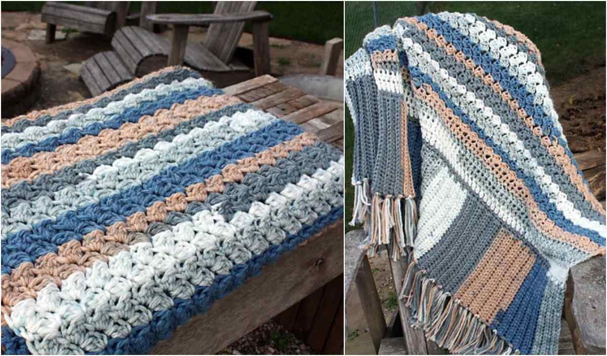 A striped crocheted blanket in blue, gray, white, and beige, reminiscent of a Baby's Dream Blanket, is draped over a wooden outdoor bench.