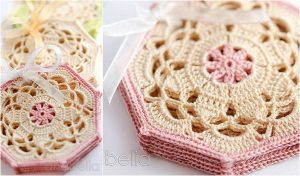 Close-up of crocheted hexagonal coasters with intricate floral patterns in beige and pink, featuring delicate edging. They're tied with ribbons, showcasing the beauty of a classic crochet pattern.