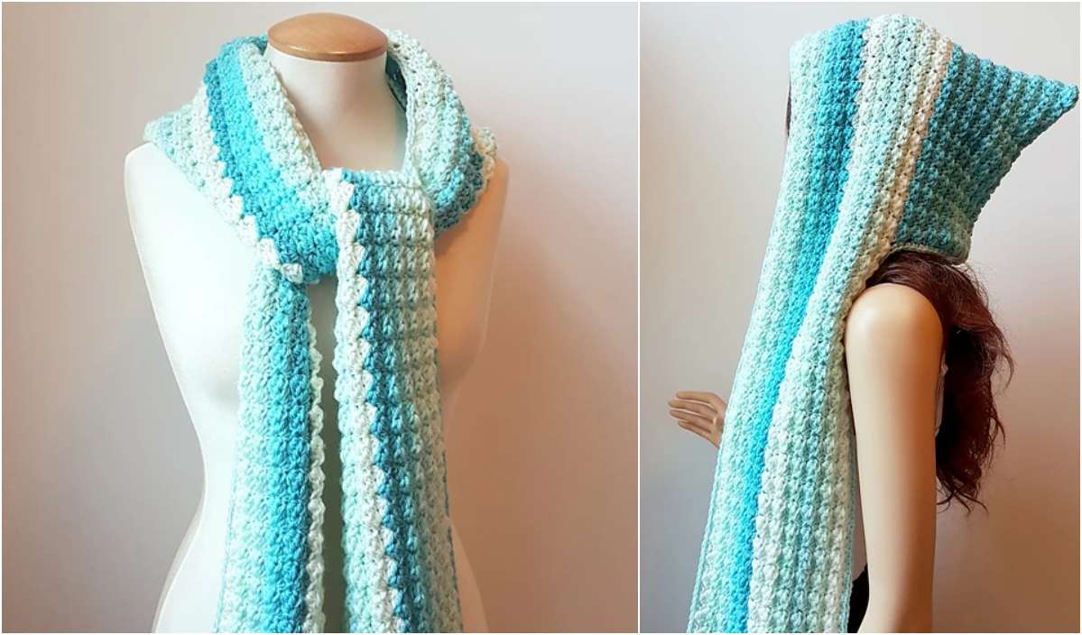 A mannequin showcases a crocheted hooded scarf, designed with blue, white, and gray stripes. The cozy accessory is elegantly worn with the hood up on the mannequin’s head, perfect for those chilly days when you crave warmth. Access this stylish look from a free crochet pattern today!