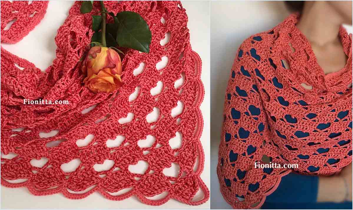 Close-up of a pink crocheted shawl with heart patterns, displayed with a rose on the left and worn over a blue top showcasing its lacy wrap design.