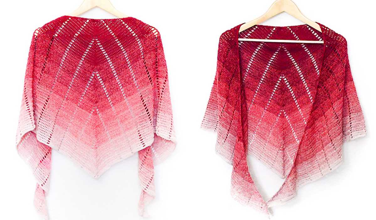 A red and pink ombre knit shawl drapes elegantly on wooden hangers, offering back and front views. Resembling a rainbow blanket's vibrant allure, this piece adds a splash of warmth to any ensemble.