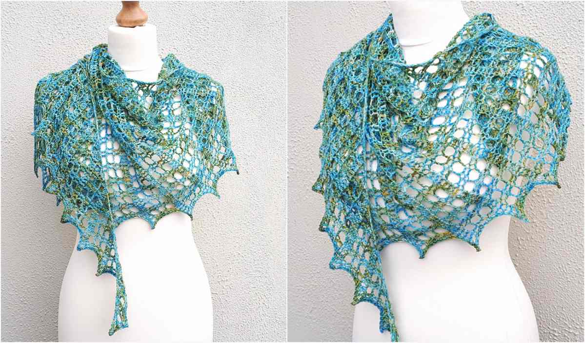 The Flora Shawl, featuring a delicate lacy pattern, is elegantly displayed on a mannequin. In shades of blue and green, this crocheted piece adds a touch of grace to any ensemble. Plus, you can recreate it with the free crochet pattern available.