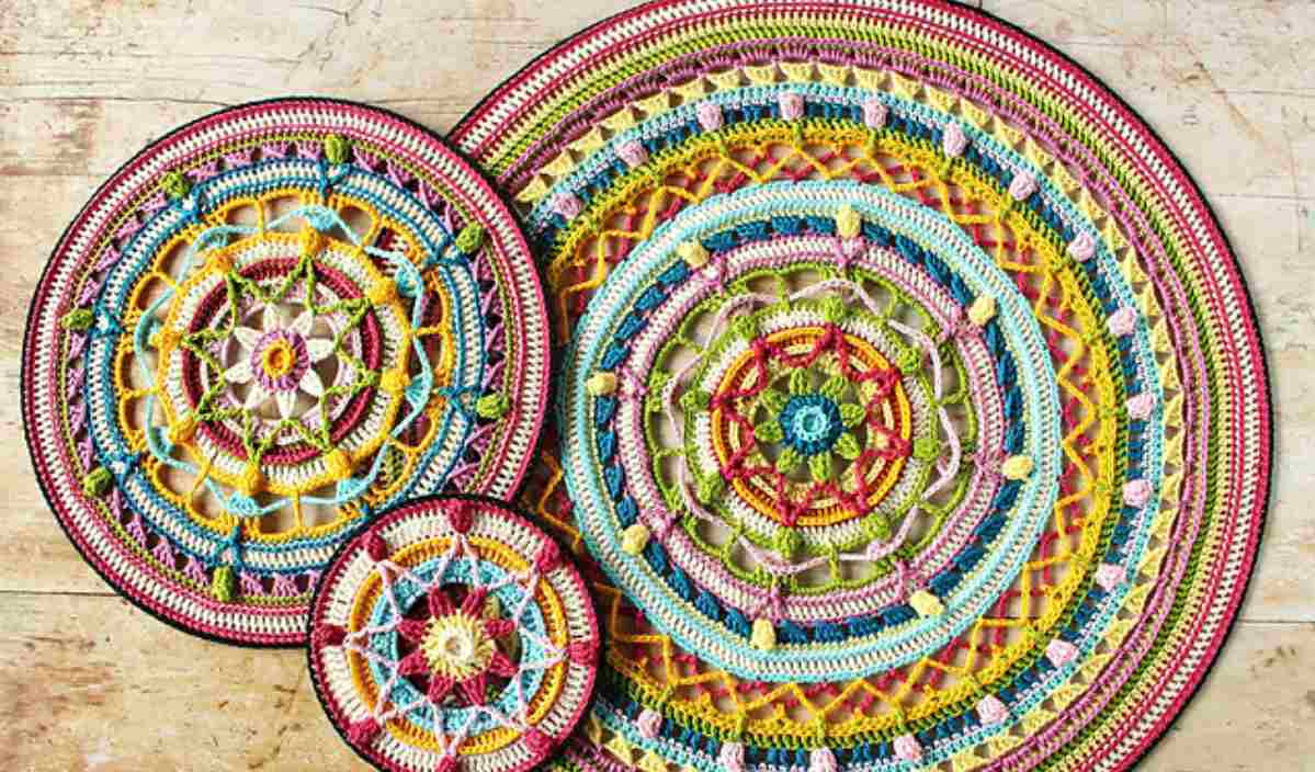 Three colorful, intricately crocheted round mandalas, crafted with a stunning linen stitch pattern, are displayed on a wooden surface.