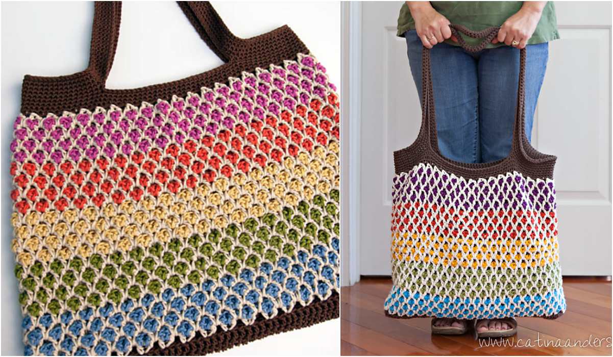 Crocheted tote bag with a rainbow-colored body and brown handles, crafted in a charming granny square design. Shown in close-up, it’s being held by a person standing indoors.