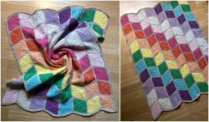 A colorful crocheted blanket with a geometric pattern, reminiscent of a free crochet pattern, is laid out on a wooden floor, boasting an array of pastel and bright hues.