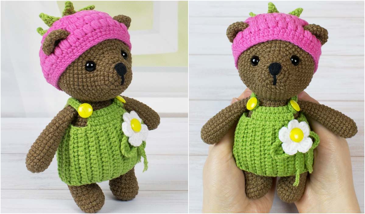 Crocheted brown teddy bear adorned with a pink hat and green dress featuring a white flower, shown standing and held. Perfect for those seeking a cute crochet pattern to add to their collection.