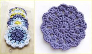 A set of crocheted flower-shaped coasters in purple, white, yellow, and blue yarn is elegantly stacked beside a standalone purple coaster. Perfect for adding charm to your table, this set comes with a crochet pattern guide to inspire more colorful creations.