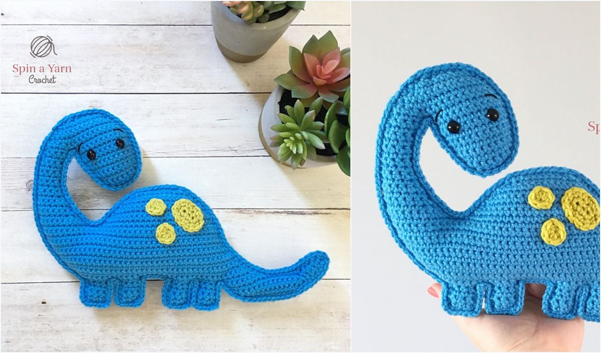 A crocheted blue dinosaur with a long neck and yellow spots is charmingly displayed on a wooden surface next to succulents, resembling the artistry of a free crochet pattern.