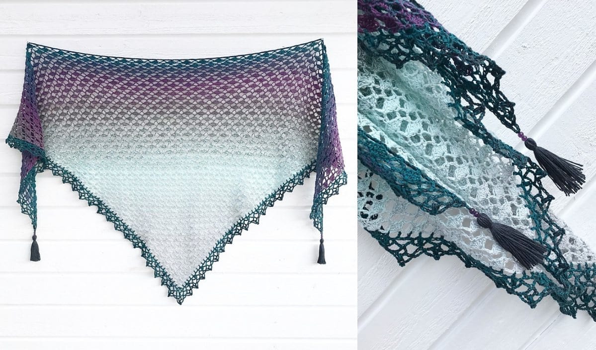 The Cotton Flower Shawl is a stunning crochet piece with gradient colors transitioning from teal to purple, featuring intricate lace patterns and tassels on the corners. Discover the artistry by creating your own with our free crochet pattern.