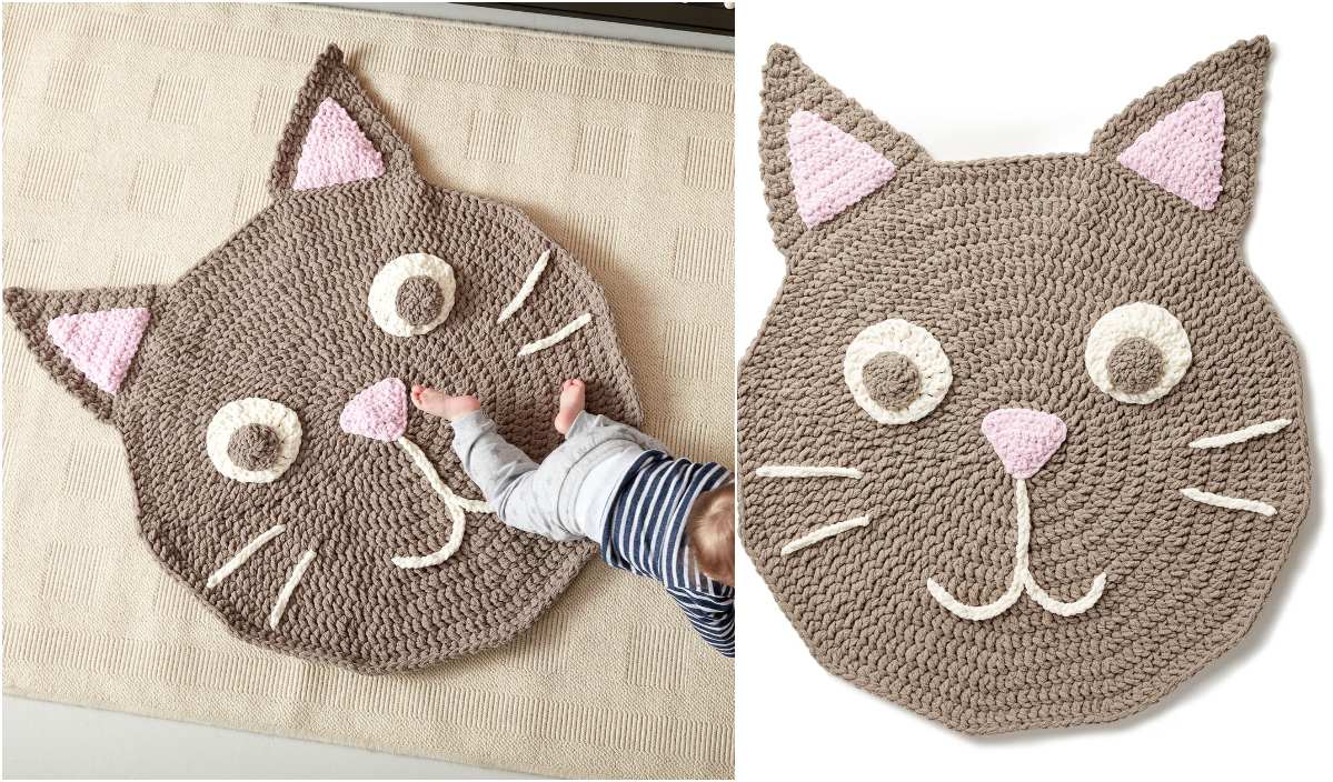 A hand gently places a small foot on a charming crochet rug shaped like a cat's face, complete with pink ears, a pink nose, and white eyes and whiskers. Ideal for DIY enthusiasts looking to create their own cozy decor with this adorable free pattern.