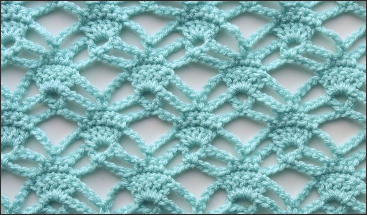 Close-up of a light blue crochet lace pattern featuring intricate triangular and diamond shapes, perfect for incorporating into your next poncho project.