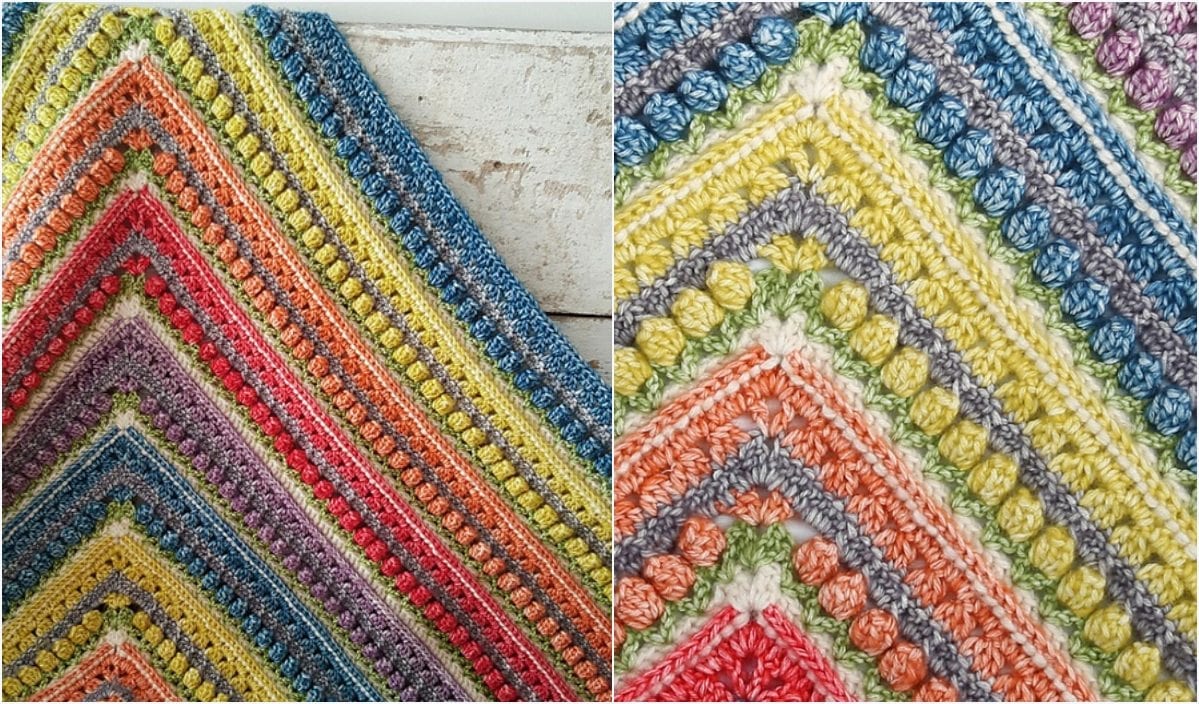 A close-up of a colorful, textured crochet blanket designed with triangular patterns reminiscent of a Triangle Shawl, showcasing vibrant stripes and bubble stitches in shades of orange, pink, purple, blue, green, and yellow.