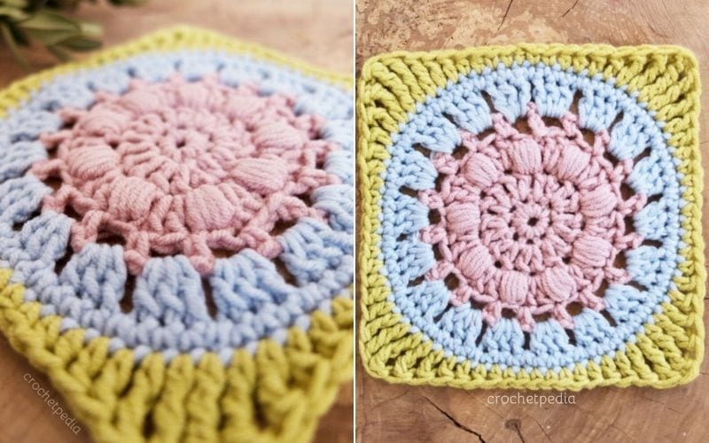 A close-up of the Calm Cove Square reveals a crocheted masterpiece with a pink and blue floral pattern, framed by a serene yellow border. Explore this art through our free tutorial and create your own tranquil piece.