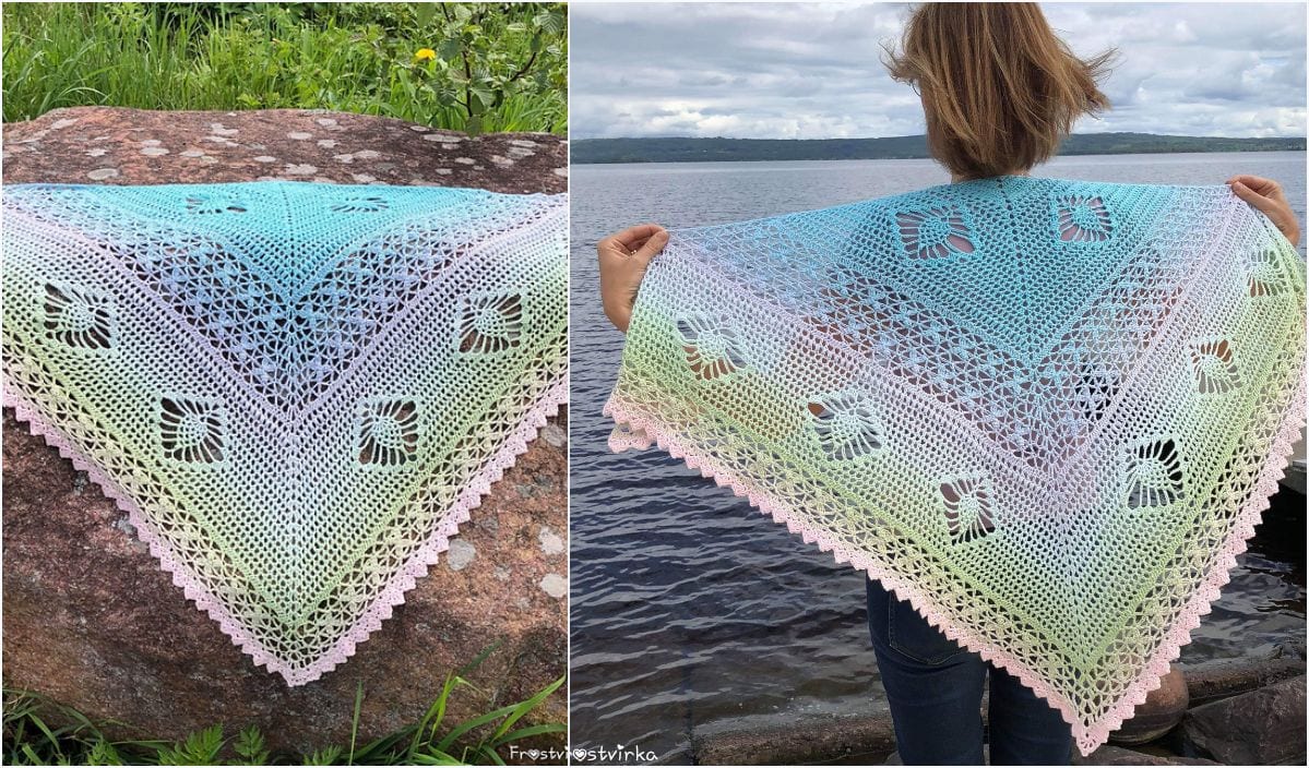 A multicolored Sunset Shawl with intricate crochet patterns is gracefully displayed on a rock and held up by a person near a lake.