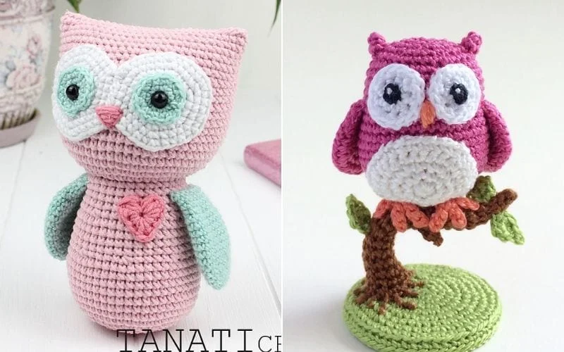 Two sweetest amigurumi owls: one pink with a heart on its chest and the other pink and white, perched on a brown crocheted branch with a green base.