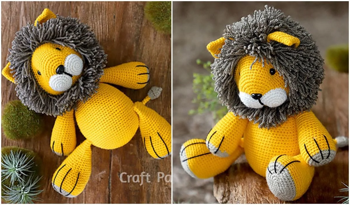 Two crocheted yellow lion plush toys, crafted using delightful crochet patterns, feature gray yarn manes, black details, and cute expressions. Displayed against a wooden background with green foliage around them.