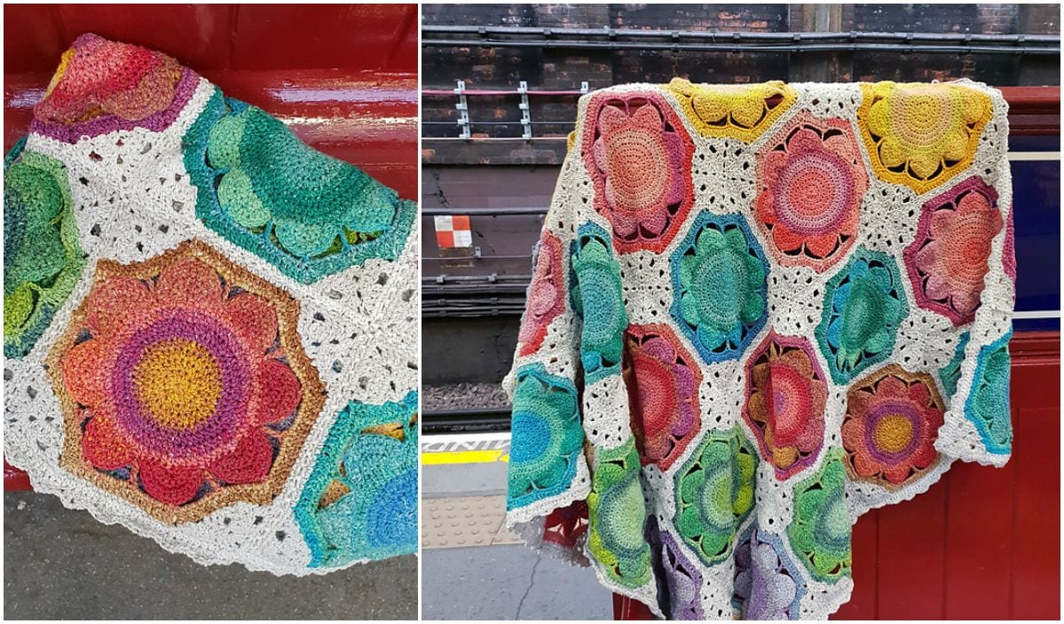 A vintage blanket with colorful hexagonal floral patterns is elegantly draped over a red railing in a train station.