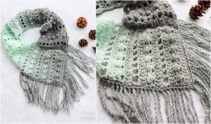 Crocheted scarf with a gradient from mint green to gray, featuring a lace pattern and fringe, alongside an angel ornament on a white surface with pinecones.