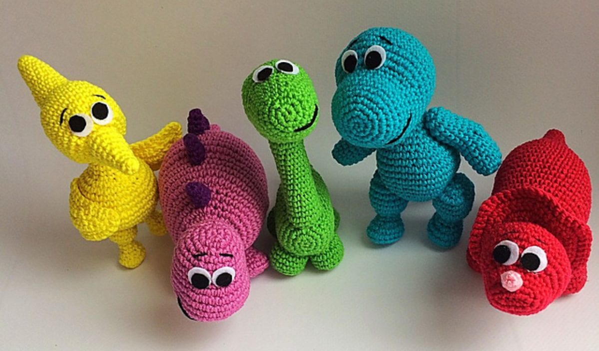 Colorful tiny dinosaur toys in yellow, pink, green, turquoise, and red, each with large googly eyes. These charming creatures are brought to life with intricate crochet patterns that delight both the young and the young at heart.