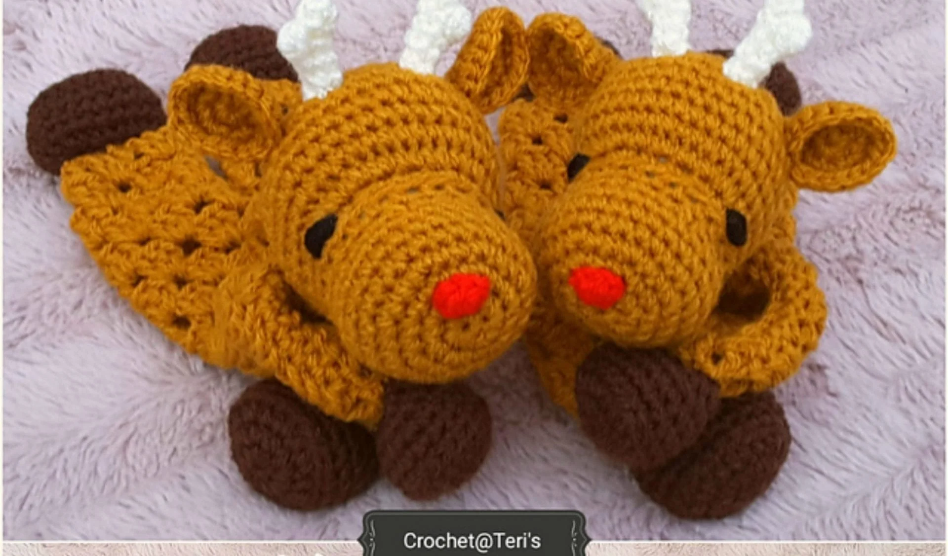 Two crocheted reindeer toys with brown bodies, white antlers, black eyes, and red noses rest side by side on a soft, light textured surface—an adorable Christmas gift idea crafted from free crochet patterns.