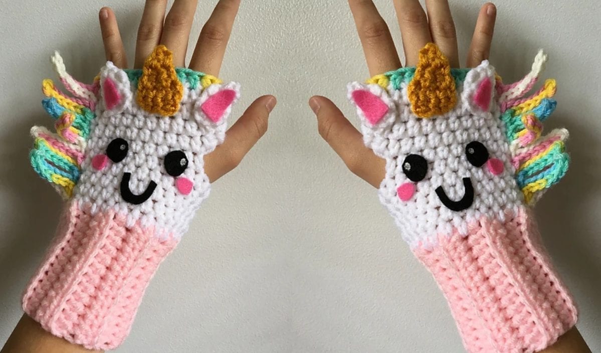 A hand adorned with whimsical, unicorn-themed fingerless gloves, featuring colorful manes and horns, captures the magic of unicorn accessories. These delightful gloves add a touch of fantasy to any ensemble.