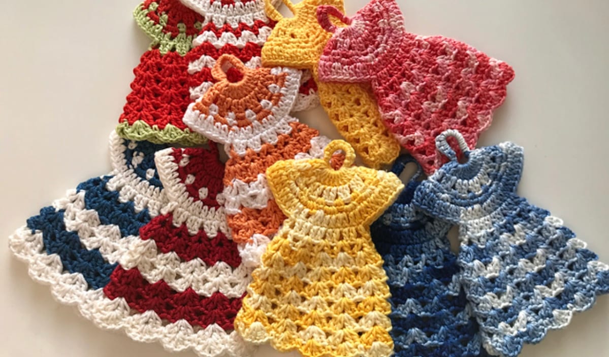 Discover the charm of crocheted doll dress potholders in vibrant hues like red, blue, orange, and pink, elegantly arranged on a white surface. Explore free crochet patterns or check out a video tutorial to craft your own exquisite collection.