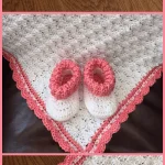 A soft baby blanket, crocheted in white with a pink border, is displayed folded alongside white baby booties with pink cuffs. Perfect for those seeking charming crochet patterns to create a cozy and delightful gift.
