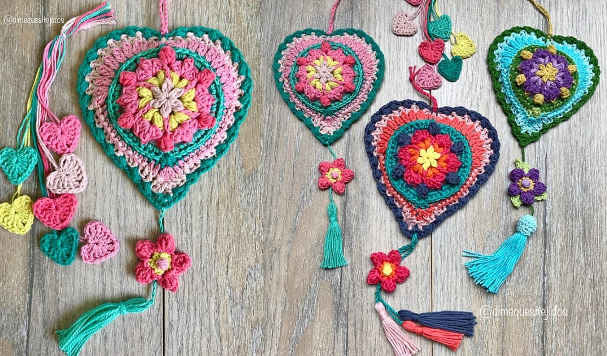 Colorful crochet hearts and flowers with tassels rest on a wooden surface, showcasing vibrant designs perfect for creating your favorite crochet patterns.