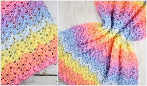 A crocheted blanket showcasing a vibrant gradient pattern with purple, blue, green, yellow, orange, and pink hues. This rainbow baby blanket design is an eye-catching treasure for any nursery.