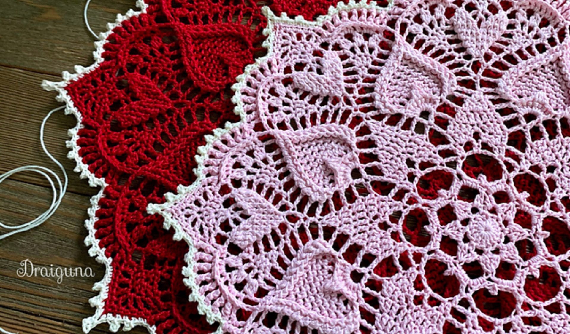 Close-up of a beautiful doily showcasing intricate heart patterns in red and pink yarn.