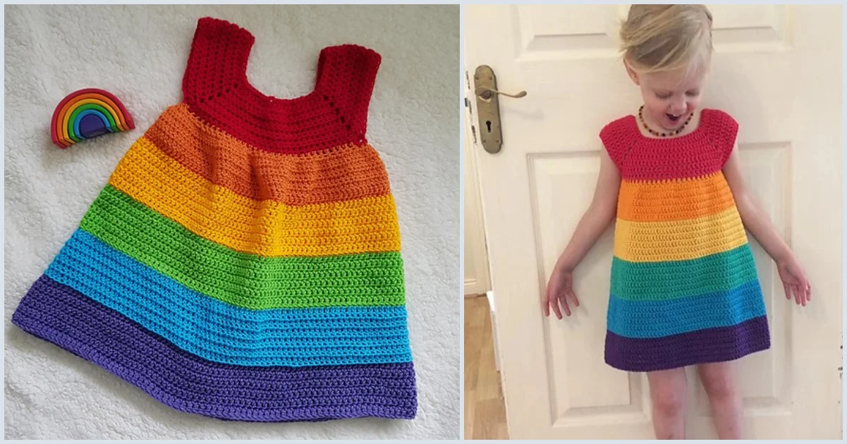 A child stands by a white door, smiling in a vibrant crocheted rainbow dress that gracefully transitions from red to purple. Beside the dress, a rainbow toy lies, completing the cheerful scene.