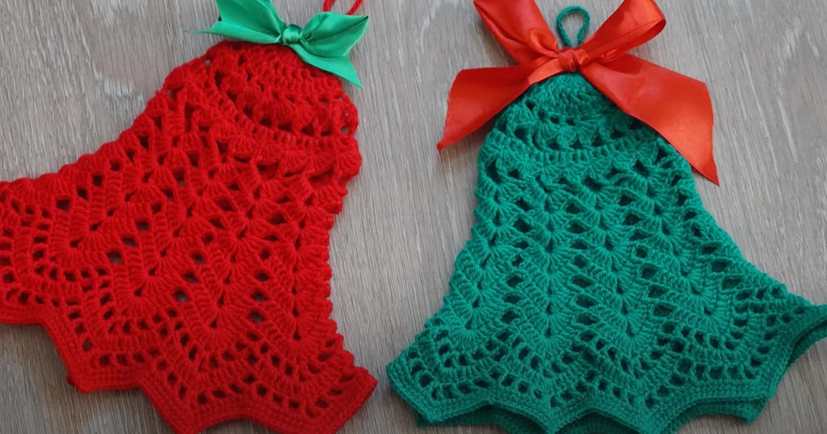 Two charming Christmas crochet bell ornaments, one red and one green, each adorned with a matching ribbon bow, rest elegantly on a wooden surface.