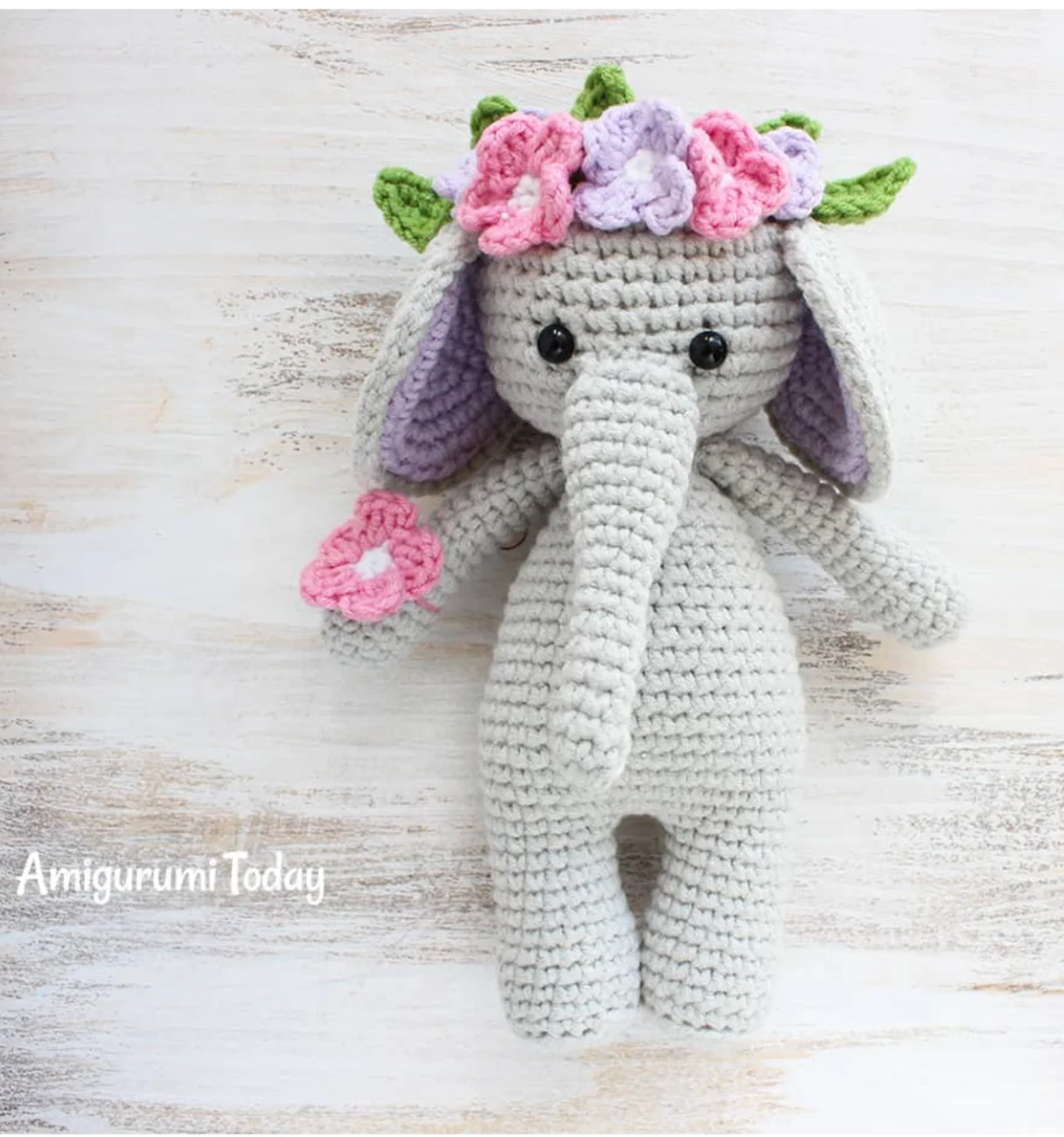 Crochet elephant toy wearing a flower crown and holding a small flower in its trunk, perfect for a free crochet elephant pattern.