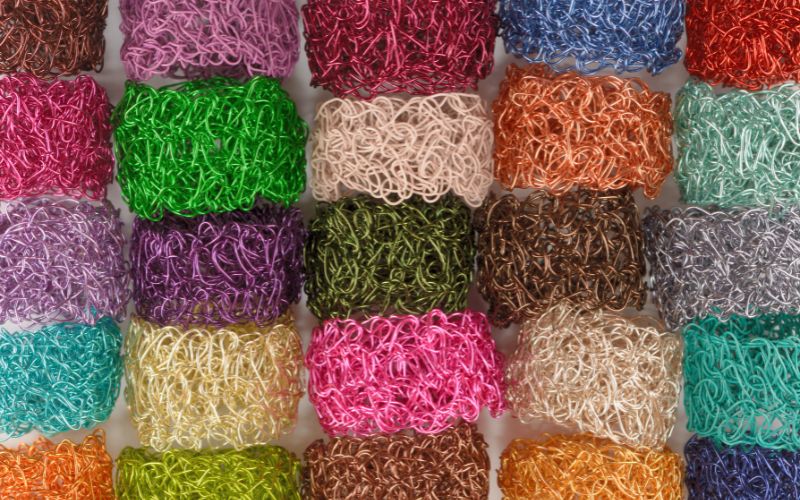 Close-up of colorful, tangled wire strands artfully interwoven in a grid, resembling intricate wire crochet.