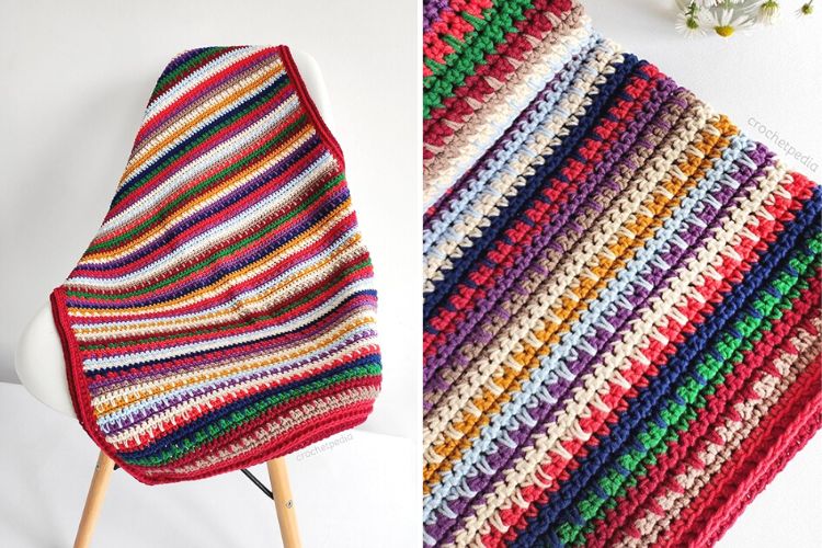 A colorful crocheted afghan in the shape of a lake sunset shawl, hanging on a chair.